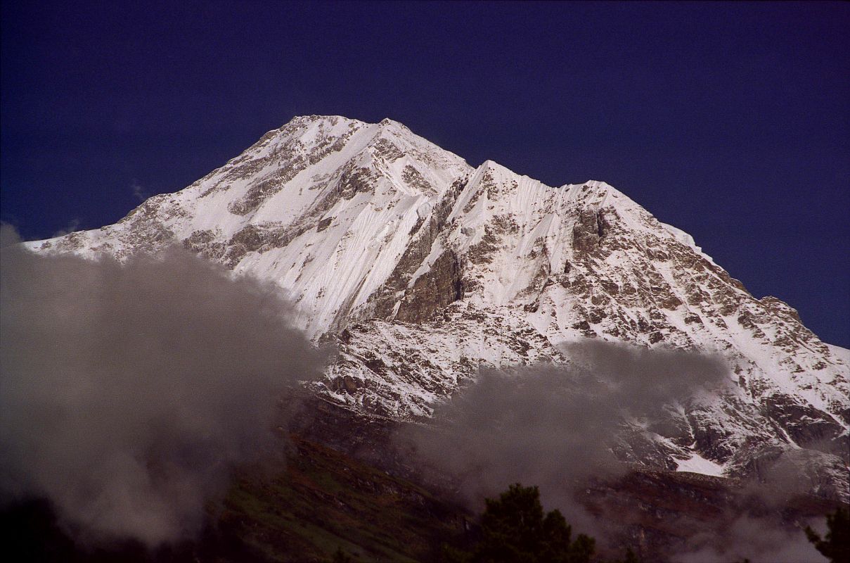 407 Dhaulagiri South Face Early Morning From Lete Above this stony desert Dhaulagiri rose into swirling clouds, vast and solitary. For twenty thousand feet there was nothing but the glint of riven glaciers, ridges that seemed like streamers in the wind, and somber rock buttresses higher than the Walker. The sight was so overwhelming that we sat down by the side of the trail feeling slightly numbed (Lionel Terray, Conquistadors of the Useless).